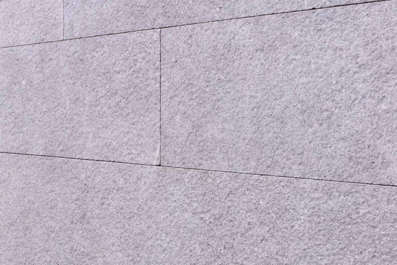 Minimalist and authentic architecture: brushed flamed gray Kahla natural stone for facades with a raw and textured appearance