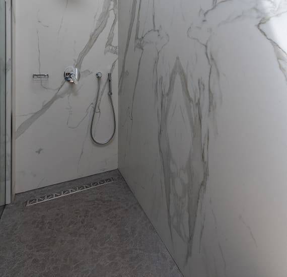 Flooring and washbasin in gray natural stone with a flamed and brushed non-slip finish for the bathroom