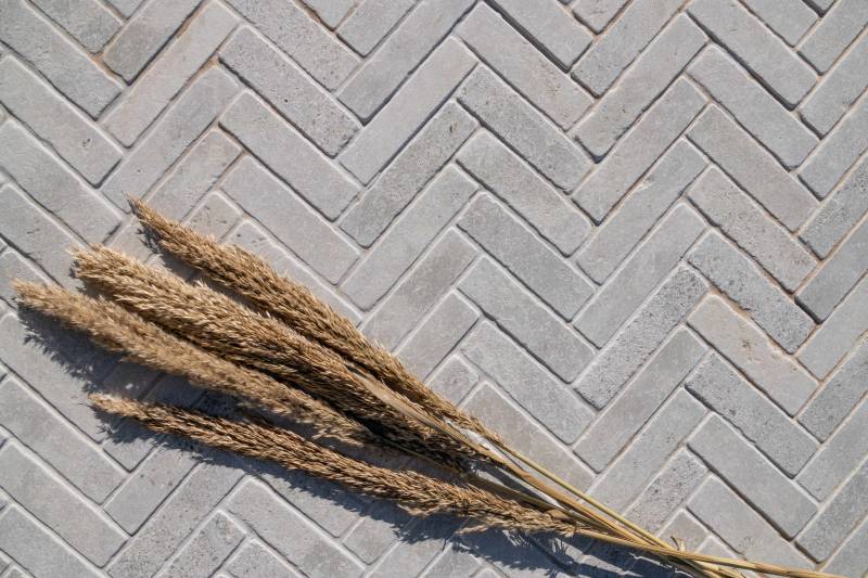 Avallon grey natural stone cobbles from Morocco in herringbone pattern – Ussé finish – elegant grey limestone paving for outdoor terrace.